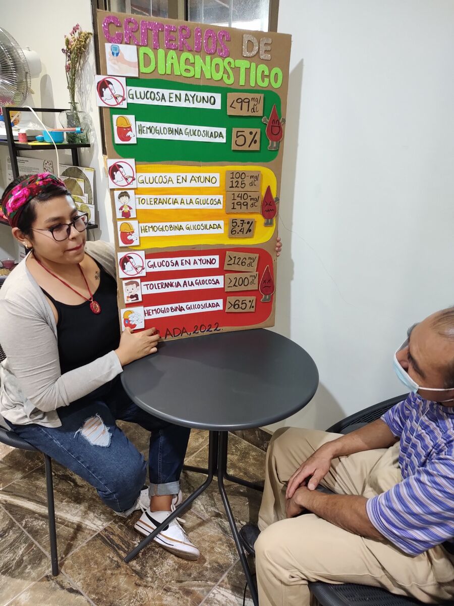 Yanely García explicando a un paciente los criterios diagnósticos de glucosa y hemoglobina glicosilada