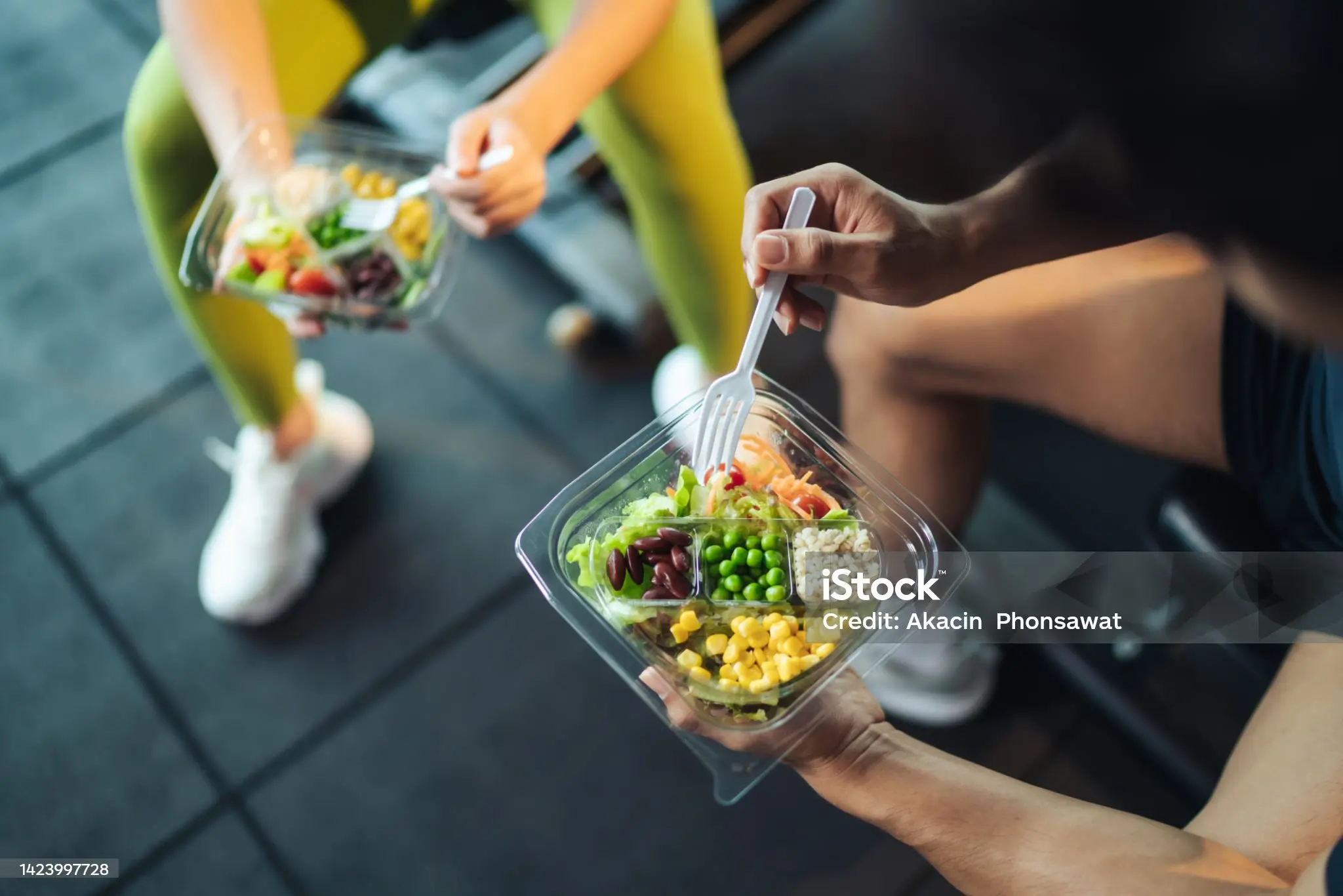 Dos personas comiendo ensaladas saludables en recipientes después de entrenar